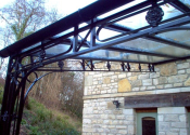 Midford Lane. Large wrought iron canopy with glass roof and lead rose detailing