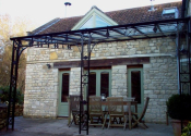Midford Lane. Large wrought iron canopy with glass roof and lead rose detailing