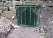 Padlocked security grille for a drain in a private garden. Finished in Mid Brunswick Green